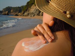 women sunbathing with sunscreen on the beach