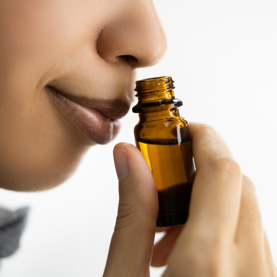 women smelling essential oils from a brown bottle